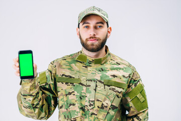 Attractive soldier in a military uniform shows his smartphone gr