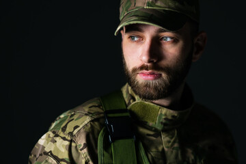 A bearded man in camouflage uniform, looking away with a sad face, yearning for his family.