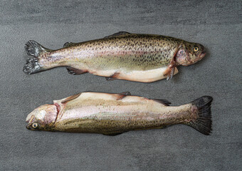 Fototapeta premium Two fresh trout fish on a dark table. Close up top view