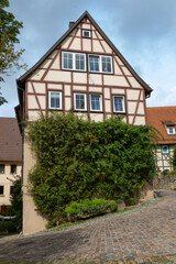 A historic, medieval half-timbered house overgrown with ivy on a descending street. The old German town of Bad Wimpfen in Baden-Wuerttemberg,, Germany. Summer photography.
