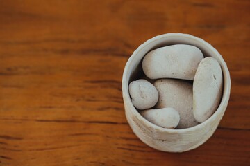 white stones in a cup over a wood table
