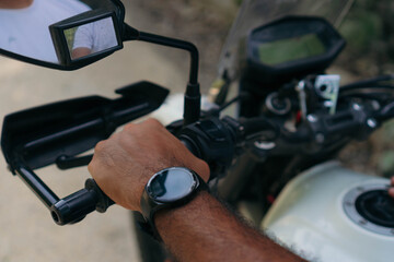 Closeup of a man sitting on his motorbike on the side of a road in the countryside