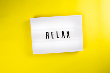 Lightbox with text message RELAX isolated on yellow background. Concept of chill, coffee break, rest, vacation, holiday, retreat, freelance remote work, summer, stress, relaxing, meditating, recharge