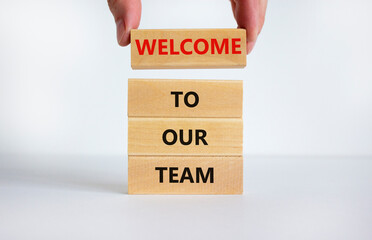 Welcome to our team symbol. Concept words 'Welcome to our team' on wooden blocks on a beautiful white background. Businessman hand. Business, motivational and welcome to our team concept.