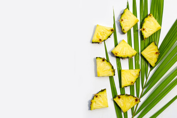 Fresh pineapple on tropical palm leaves on white background.