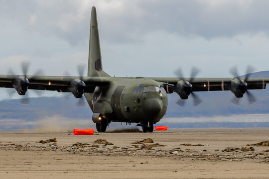 A Royal Air Force C-130 Performing Tactical Landings And Takeoffs From The Public Beach At Cefn Sidan Sands In West Wales.