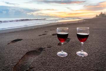 Romantic beach sunset toast with two glasses of red wine. Luxury honeymoon and anniversary celebration background