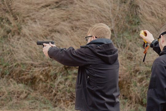 Man fires automatic handgun pistol during training in practical shooting. Man with gun, gangster. Blur crazy young man aiming automatic gun at target. 25 April 2021, Ryazan, Russia