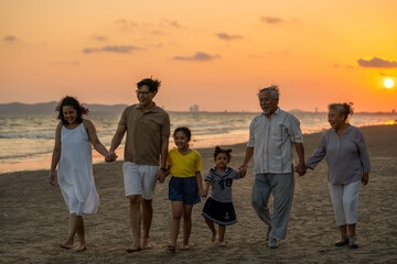 Happy big Asian family on beach holiday vacation. Multi-generation family holding hands and walking...