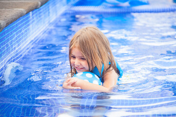 Little girl with a ball in a swimming pool