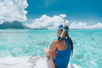 Snorkeling from boat in Bora Bora, Tahiti, French Polynesia. Woman jumping in crystal clear water...