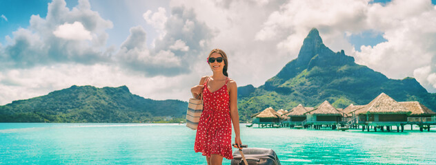 Traveling woman walking with luggage in French Polynesia on paradise Motu on Bora Bora with Mount Otemanu. Woman arriving on dream vacation destination