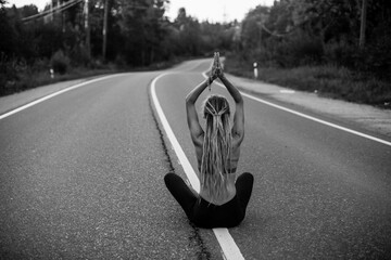 Yoga woman in lotos pose sit on the road. Black and white photo.