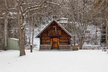 Miniature snow-covered log cabin. A cute and creative garden shed.