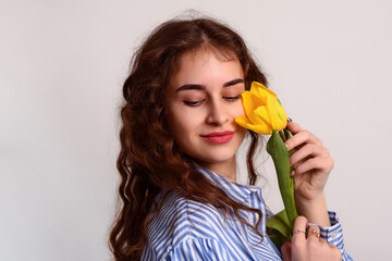 Portrait of a young woman with yellow a tulip flower close-up on a white background.