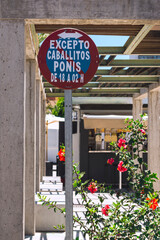 Fototapeta na wymiar Sign of Prohibited to park ponies and Horses, next to a rosebush of flowers.The photograph is made in vertical format and was taken on a street in Andalusia, Spain.