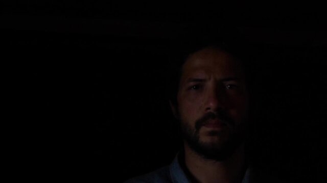 Bearded Man With Serious Facial Expression Coming Out Of The Dark. close up, studio shot