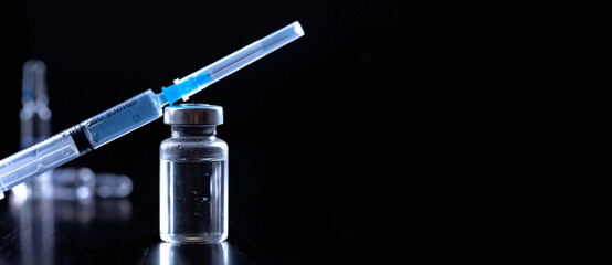 Medical syringe with a needle and a bollte with vaccine.