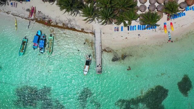 Cinematic downward angle drone shot starting on a pier then rising to reveal the resort beach at Mahahual Mexico