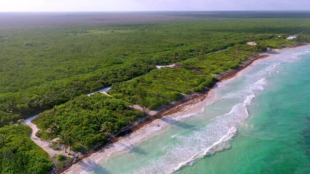 Wide cinematic rotating drone shot of natural coastline near Mahahual Mexico into the sun