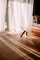 Modern room interior with an open window in minimal style. Transparent tulle with morning sun rays...