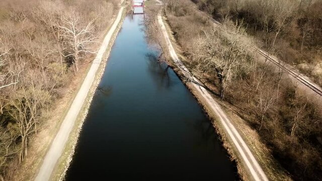Low aerial drone view following the Hennepin Canal and Parkway Trail in early spring in Colona Illinois; an abandoned waterway in northwest Illinois, first canal built of concrete and opened in 1907