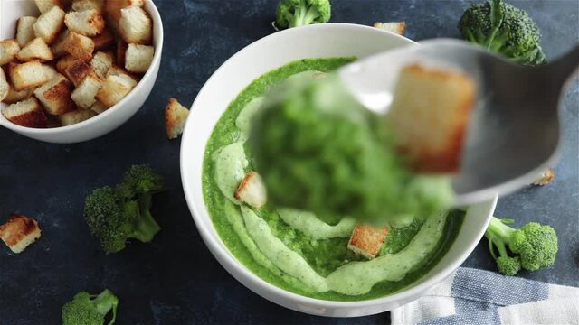 eating healthy broccoli puree soup with croutons first person view 