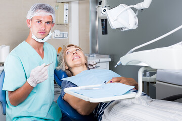 professional male dentist with female patient during oral checkup in dentistry