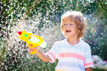 Kids with water gun toy in garden. Outdoor fun.