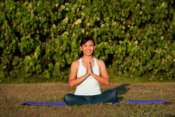 people, fitness, sport and healthy lifestyle concept-sportive thoughtful pensive beautiful charming asian woman with close eyes practicing yoga outdoor in the park