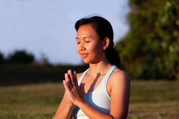 people, fitness, sport and healthy lifestyle concept - close up portrait of thoughtful pensive beautiful charming asian woman making yoga meditation outdoor