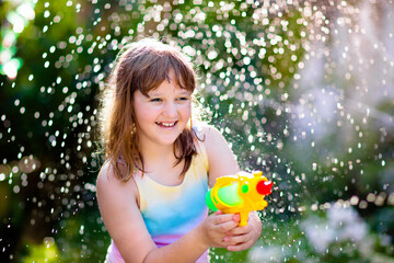 Kids with water gun toy in garden. Outdoor fun.