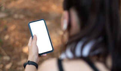 Young sporty woman holding mobile phone with blank screen indoors, closeup view. Mockup for design.
