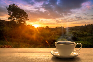 Close up white coffee cup on wood table and view of sunset or sunrise background