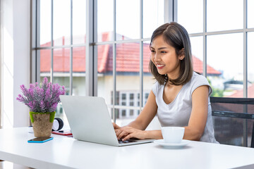 Portrait of Asian woman freelancer working at home, sitting at desk table in living room