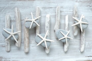 Driftwood. White sea driftwood, gray stones and white starfishes on a light shabby chic wooden background.Home decor and wallpaper in a nautical style.Driftwood decor in minimalism style in gray tones