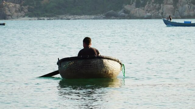 Fisherman paddling bamboo basket boat, beach of Vinh Hy Bay, Vietnam