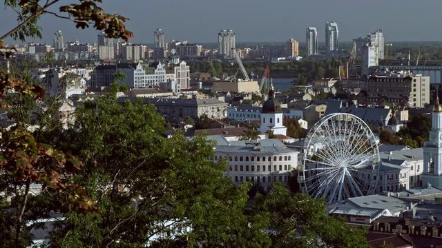 Static telephoto clip of Podil district of Kiev framed by autumn trees.