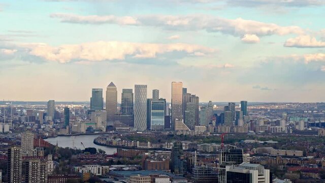 Panning aerial shit showing London Skyline in Canary Wharf District and Cityscape during sunny day with colorful sky.