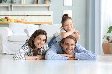 Young Caucasian family with small daughter pose relax on floor in living room, smiling girl kid hug...