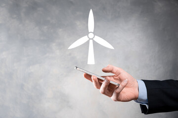 Businessman holding an icon of a windmill that produces environmental energy.