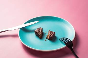 Uneaten sweet dessert chocolate bar with fork on colored plate on pink background. 