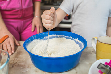 The hands of a child who mixes the dough. Cooking at home