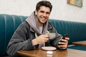 Smiling young casual man in earphones listening to music