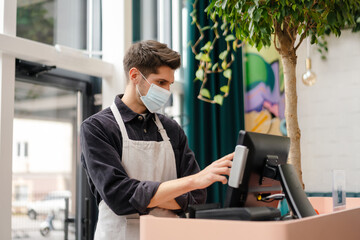 Fototapeta premium Young man in apron wearing protective medical mask