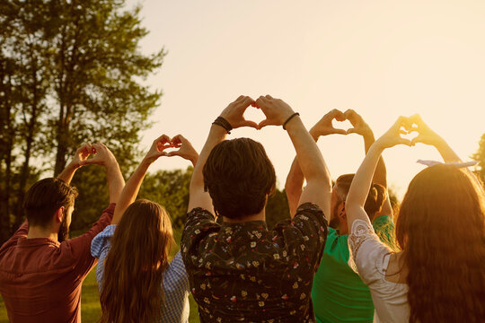 Hand sign heart. A group of people holds hands with a heart sign on a sky background with sunset on nature.