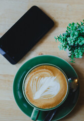 cups of latte coffee with latte art on wooden background. Beautiful foam, greenery ceramic cups