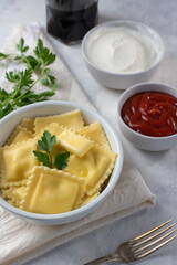 Russian dumplings or Italian ravioli with ketchup and sour cream on a light background. With cheese and mushrooms. Delicious food