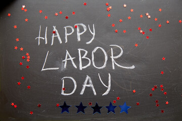 Fototapeta na wymiar Happy labor day text with chalk on chalkboard close up. Festive alstroemeria flowers stars in american style. High quality photo