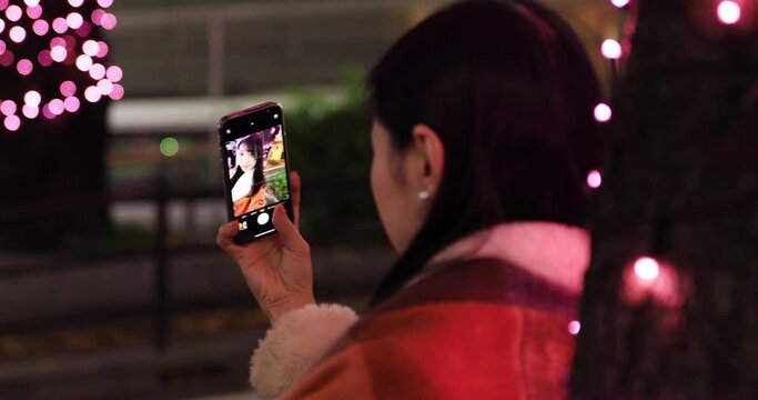 Selfie shot of Japanese woman with illumination on the downtown street closeup